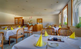 a large dining room with multiple tables covered in white tablecloths and served by yellow napkins at Hotel Astor