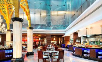 a large hotel lobby with a buffet - style dining area , where people are enjoying a meal at Le Meridien Coimbatore