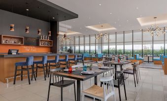 a modern restaurant with wooden tables , chairs , and a bar , as well as large windows offering views of the city at Park Inn by Radisson North Edsa