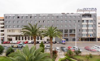 a large hotel building with palm trees in front of it , surrounded by a parking lot at Hotel Olympia Valencia