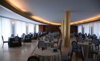 a large dining room with multiple tables and chairs arranged for a group of people to enjoy a meal together at Hotel Royal