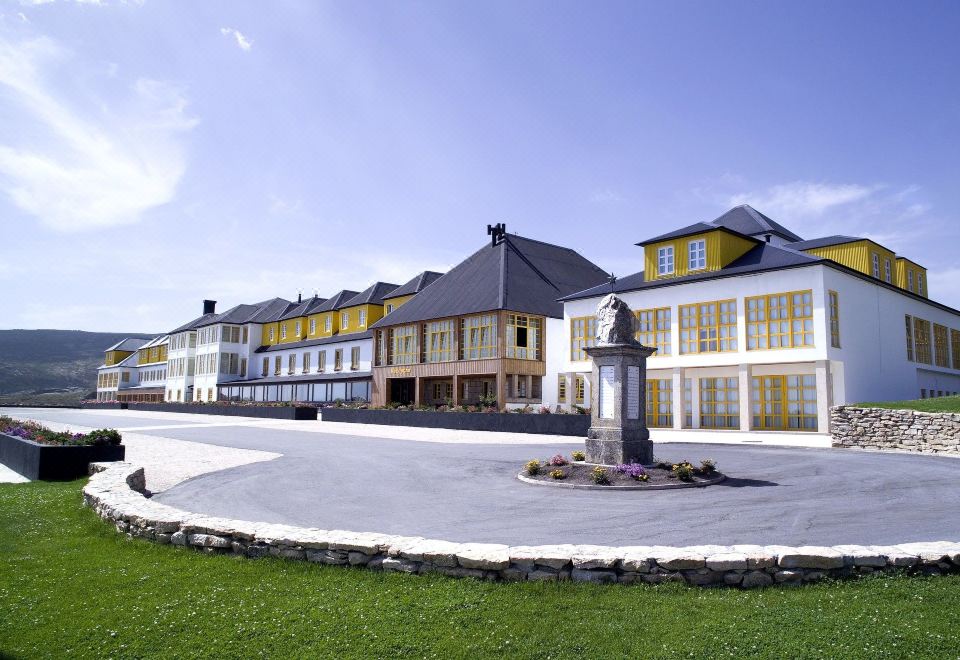 a large building with a statue in front of it , surrounded by a grassy area at Luna Hotel Serra da Estrela