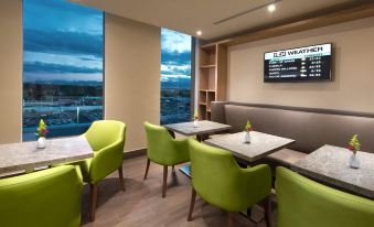 a modern lounge area with green chairs and a large window , providing a view of the city at Hilton Garden Inn Monterrey Airport