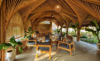 a wooden structure with thatched roof , surrounded by chairs and tables , in an outdoor setting at Lahana Resort Phu Quoc & Spa