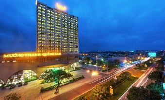 a large building with a high - rise tower and many windows is lit up at night at Muong Thanh Grand Quang Nam