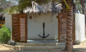 a tropical scene with a white wall , palm trees , and an anchor - shaped metal anchor against the white wall at Dolphin Beach Resort