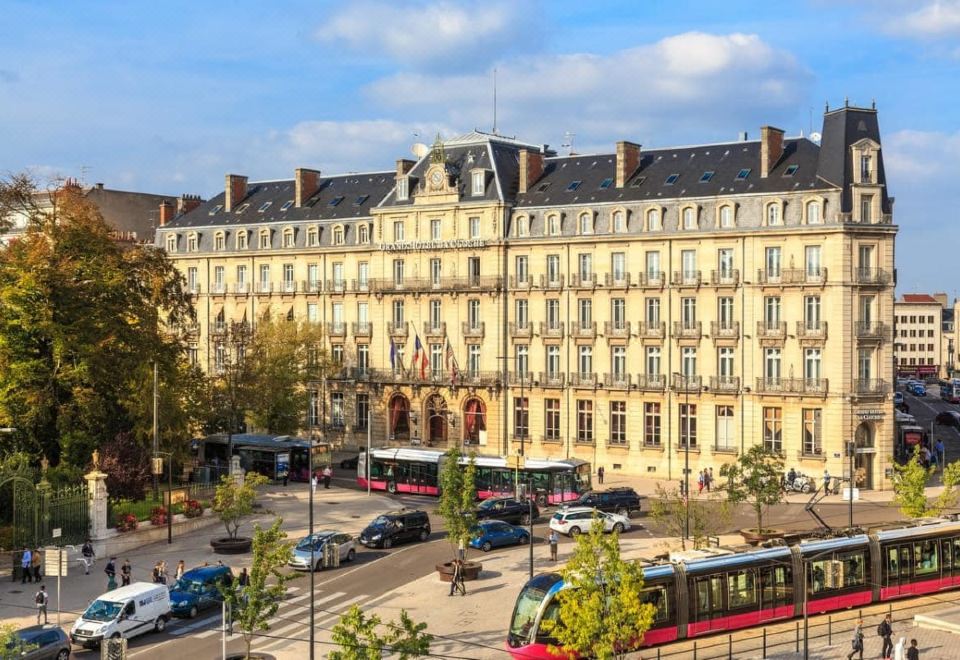 a busy city street with multiple cars , buses , and trucks , as well as pedestrians walking on the sidewalk at Grand Hotel la Cloche Dijon - MGallery