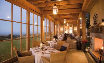 a large dining room with wooden beams and floor - to - ceiling windows , filled with tables and chairs set for a meal at Rosewood Cape Kidnappers