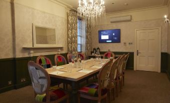 a conference room with a large table surrounded by chairs and a chandelier hanging from the ceiling at Angel Hotel