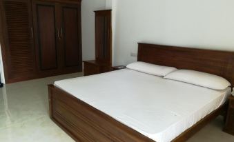 a large bed with a wooden headboard and footboard is in a room with white walls at Sea Breeze