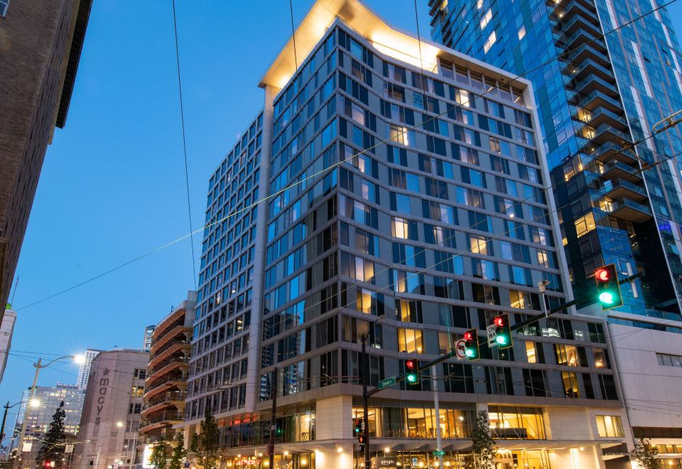 a modern building with a large glass facade and a traffic light in the city at night at The Charter Hotel Seattle, Curio Collection by Hilton