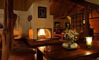 a cozy living room with a wooden dining table , a fireplace , and a large picture frame on the wall at Elewana Lewa Safari Camp