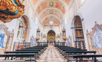 a large , ornate church interior with rows of pews and a golden altar at the front at Convento do Espinheiro, Historic Hotel & Spa