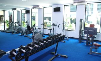 a well - equipped gym with various exercise equipment , including dumbbells and treadmills , positioned against blue flooring at Chon Inter Hotel