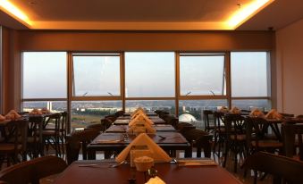 a dining room with several tables and chairs , along with a large window overlooking the city at Hplus Vision Executive