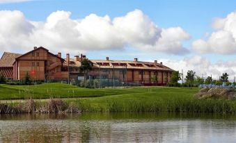 a large building surrounded by a grassy field and a body of water , creating a picturesque scene at Exe Layos Golf
