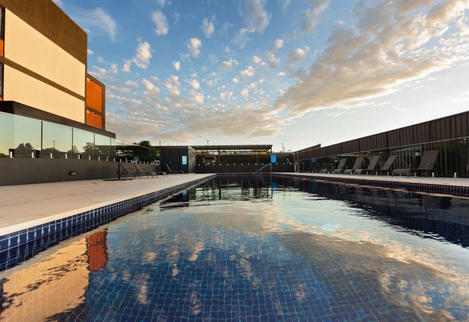 a large , blue swimming pool with clear water and surrounding facilities , set against a cloudy sky at The Penthouse