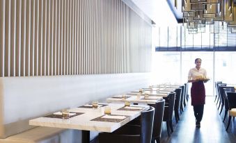 The dining room is modern and features long tables and chairs, as well as a centerpiece in the center at Bangkok Marriott Hotel Sukhumvit