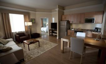 a spacious living room with a couch , coffee table , and kitchen in the background , as well as a kitchen area with appliances at Homewood Suites by Hilton Augusta, ME