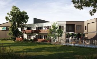 a modern , two - story building with white walls and wooden balconies , surrounded by lush green trees and a grassy lawn at Quest Bendigo Central