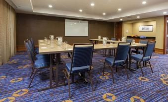 a conference room with multiple tables and chairs , a projector screen , and blue carpeting , ready for a meeting or presentation at Courtyard Rochester Brighton