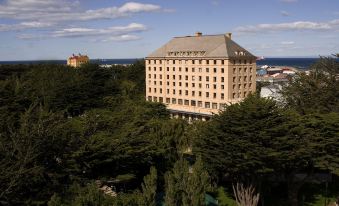 a large building surrounded by trees , with a body of water visible in the background at Hotel Cabo de Hornos