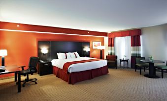 a modern hotel room with a large bed , red walls , and a desk area near the window at Holiday Inn Birmingham - Hoover