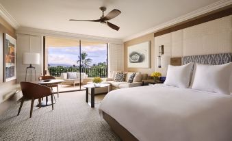 a luxurious hotel room with a king - sized bed , a flat - screen tv , a balcony overlooking the ocean , and comfortable furniture at Four Seasons Resort Maui at Wailea
