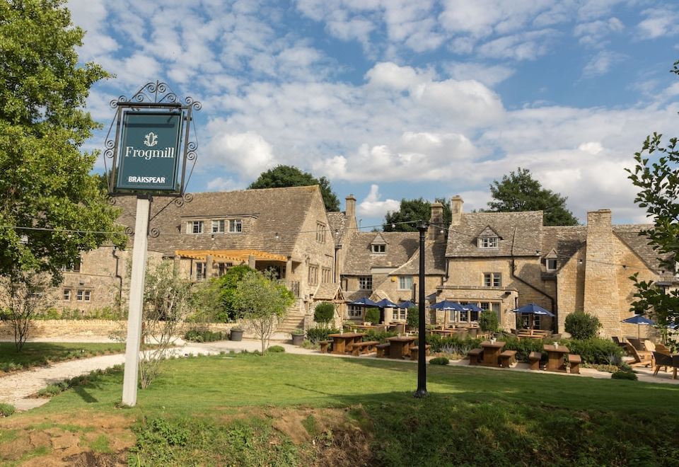 "a large stone building with multiple chimneys , surrounded by a lush green garden and a sign for "" inn of the three rivers .""." at The Frogmill Hotel