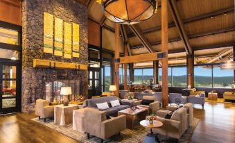 a large , open living room with high ceilings , stone walls , and wooden floors , featuring comfortable seating arrangements and a bar area at Sunriver Resort