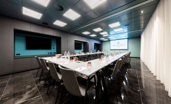a large conference room with a long table and multiple chairs arranged for a meeting at NH Collection Antwerp Centre