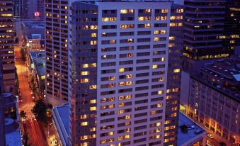 a tall building with many windows is lit up at night , surrounded by other buildings at Sheraton Grand Seattle