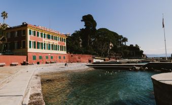 a picturesque waterfront scene with a large building , possibly a hotel , surrounded by palm trees at Hotel Metropole