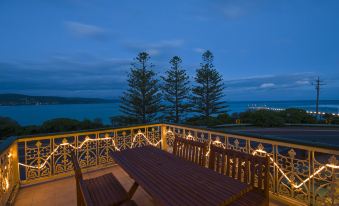 a wooden table and chairs on a balcony with a view of the ocean at night at Grand Pacific Hotel