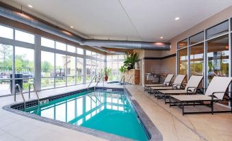 a modern indoor swimming pool area with large windows , comfortable lounge chairs , and a terrace at Cambria Hotel Appleton