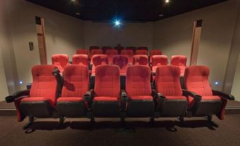 a theater with red reclining seats and a projector screen , ready for use due to covid - 1 9 pandemic at Space Hotel