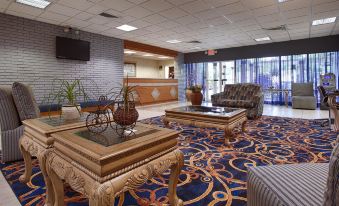 a hotel lobby with a reception desk , chairs , and couches arranged for guests to relax at Ramada by Wyndham Cocoa