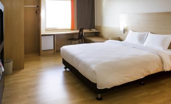 The bedroom features a double bed, a desk, and a large window with a view of the city skyline at Remis Hotel