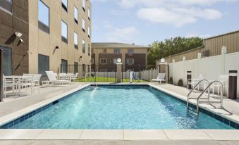 a large swimming pool is surrounded by lounge chairs and a white fence in front of an apartment building at Comfort Inn & Suites