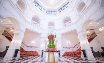a grand lobby with a checkered floor , white columns , and a large vase of flowers on a pedestal at Rizal Park Hotel