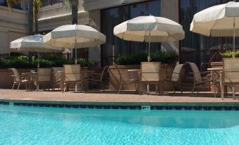 a hotel pool area with several umbrellas and chairs , providing shade and comfort for guests at Grand Hotel