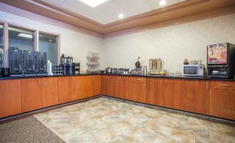 a breakfast buffet with various food items and beverages , such as coffee , juice , and pastries , arranged on wooden counters at Hotel Estevan