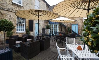 an outdoor dining area with several tables and chairs , some of which are covered by umbrellas at The Blue Boar