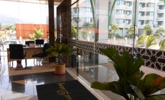 a lobby area with a potted plant , a glass door , and a welcome mat near the window at HIG Hotel