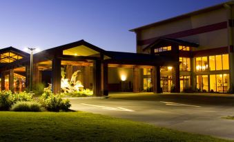 a large building with a covered entrance and lit up entrance , surrounded by grass and trees at Blue Lake Casino and Hotel