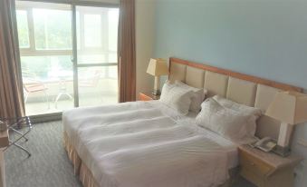 a large bed with white sheets and pillows is in a room with a window at Ocean Hotel