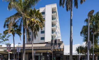 a white building with palm trees in front of it , under a clear blue sky at Rydges Mackay Suites, an EVT hotel