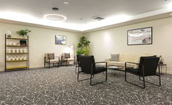 a large , well - lit room with multiple chairs and couches arranged for a group of people to sit and relax at Sage Hotel Wollongong
