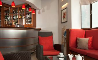 a cozy bar with red and gray furniture , including two chairs , a coffee table , and a vase at Ibis Styles Paris Mairie de Montreuil