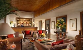 a luxurious living room with brown leather couches , wooden furniture , and a glass coffee table at Ascott Jakarta